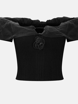 Black off-shoulder ruffled knit t-shirt with sheer sleeves and a floral applique.