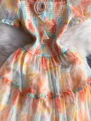 Floral tiered midi dress with smocked bodice and sheer sleeves in a pastel tie-dye print.