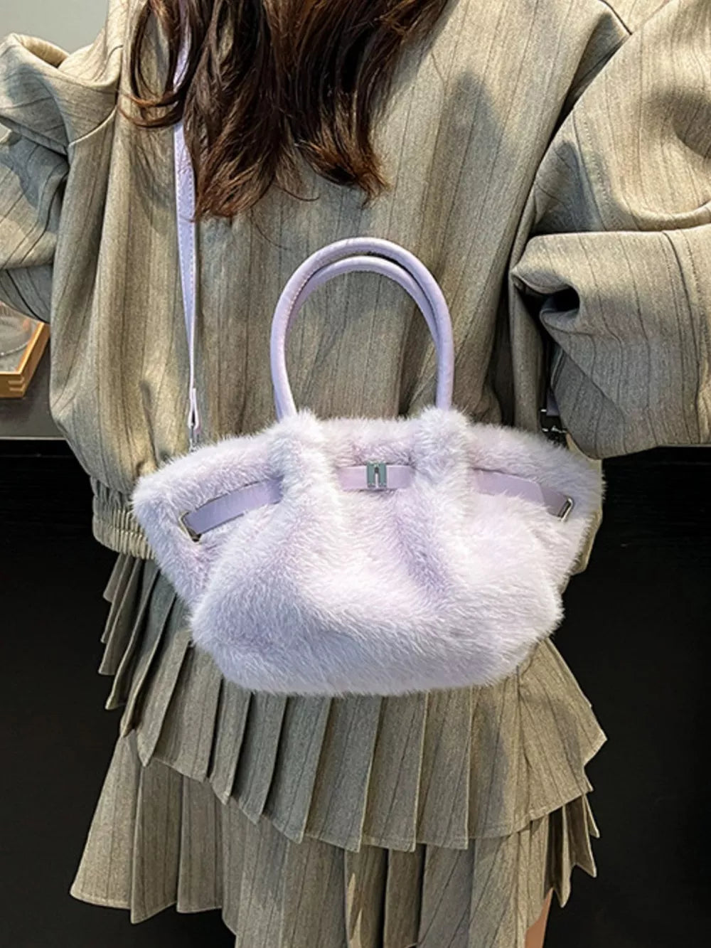 Plush crossbody bag in purple with chic buckle detail and top handles.