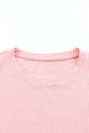 Blush pink ribbed knit blouse with crew neck and visible stitching detail.