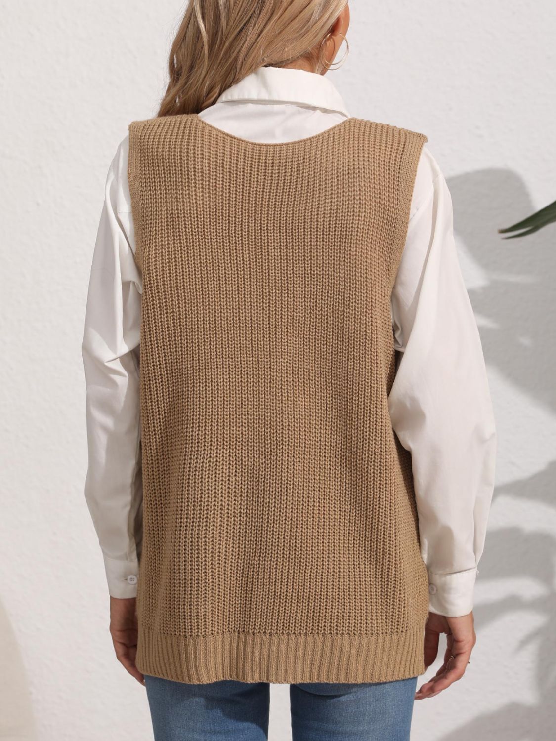 Oversized camel knit vest with ribbed texture and a rounded neckline, styled over a white shirt.