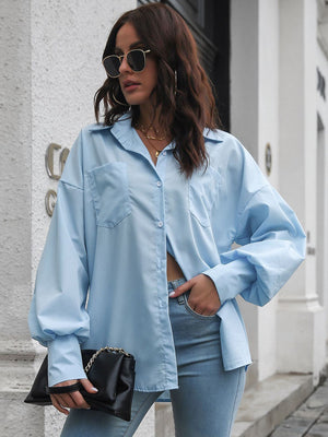 Blue oversized poplin blouse with blouson sleeves and button front, styled with jeans.