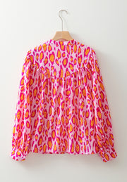 Pink leopard print blouse with balloon sleeves and a mock neck.