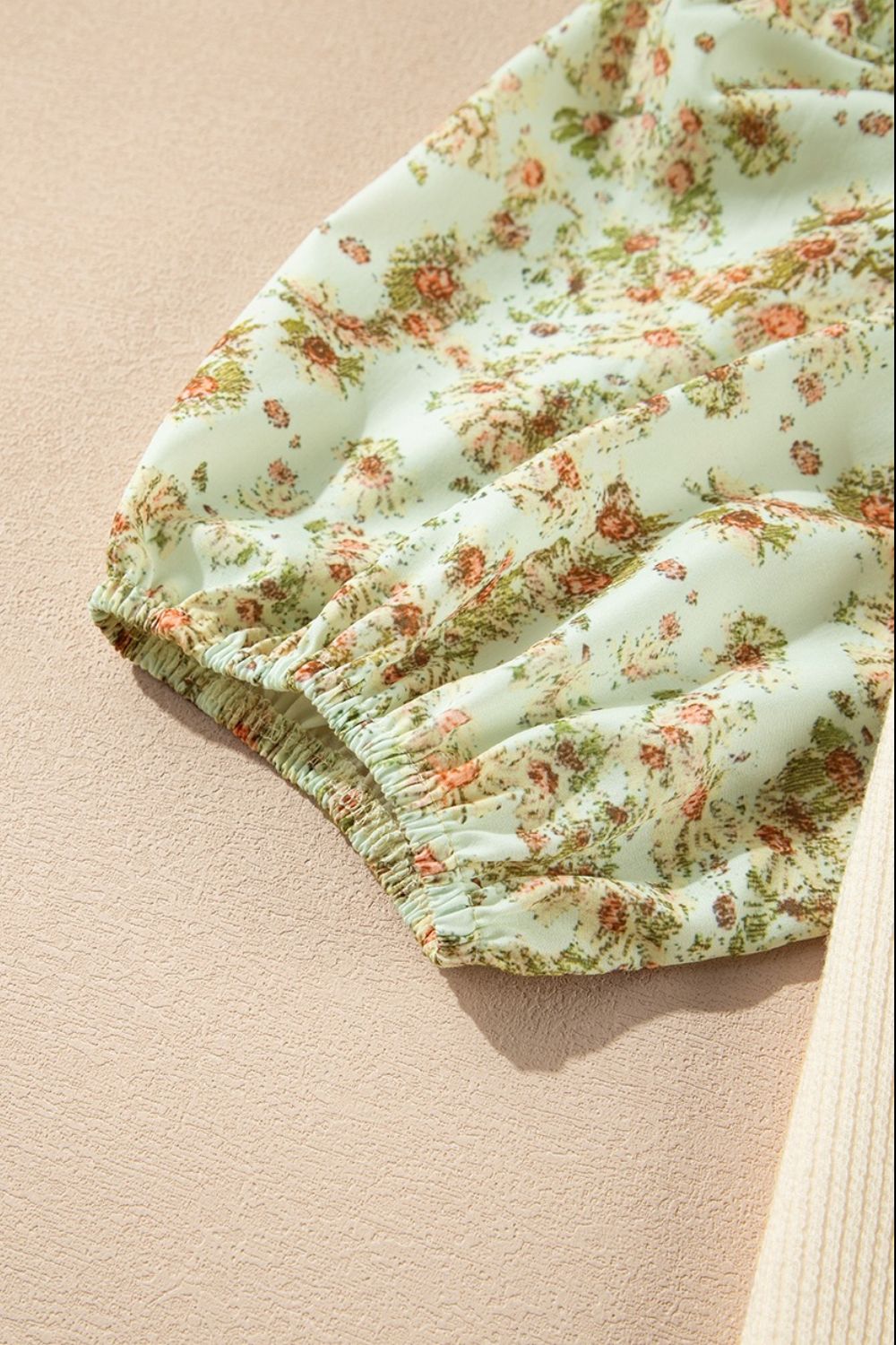 Floral puff sleeve blouse in beige with gathered cuffs and a delicate floral print.