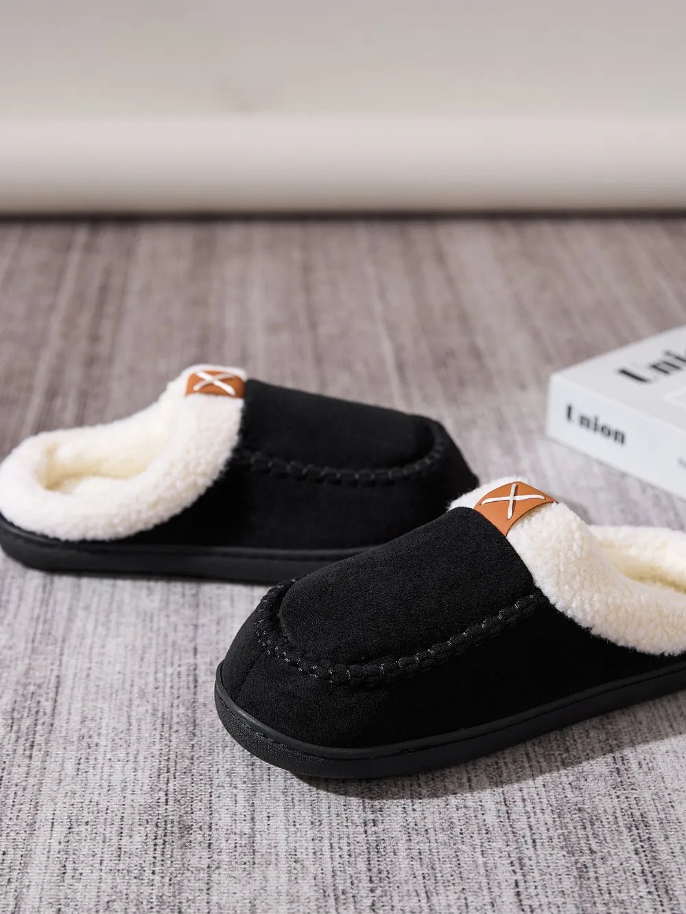 Black suede shearling-lined moccasin slides with contrast stitching and leather detail.