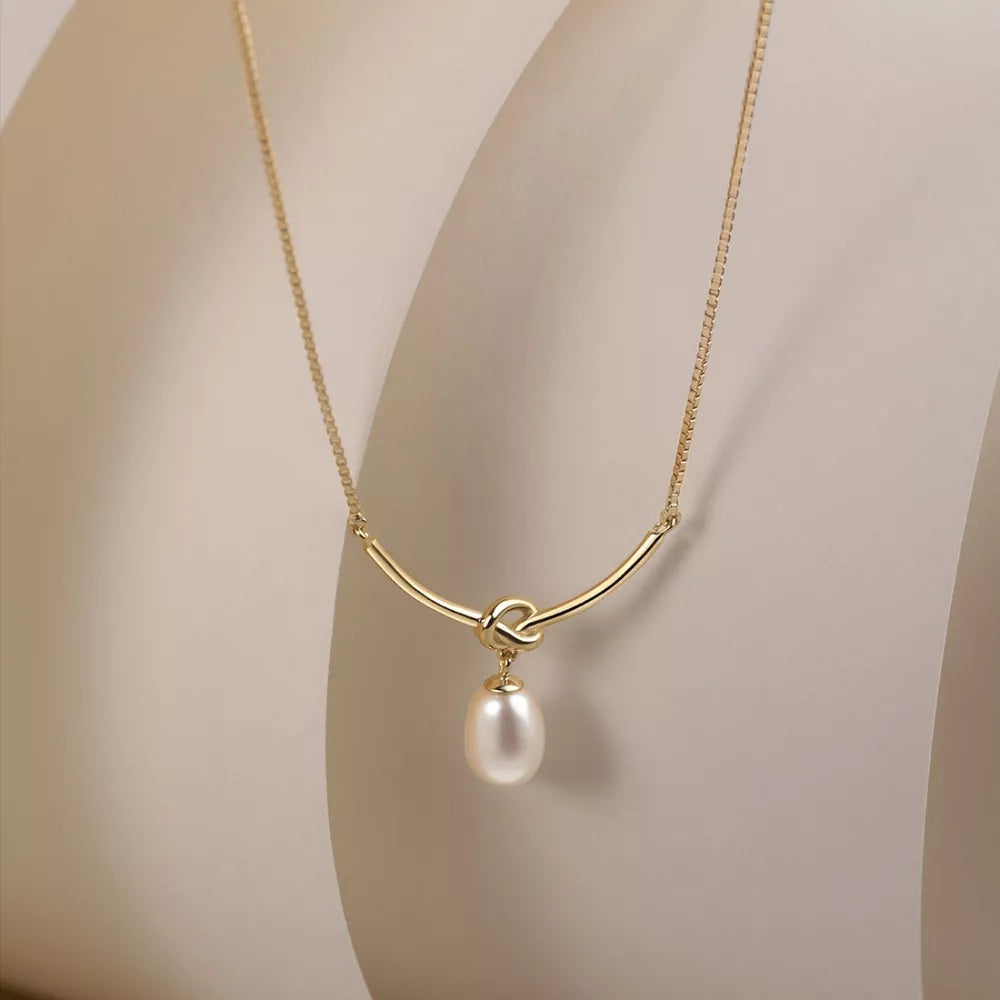 Gold necklace with knot detail and lustrous pearl pendant
