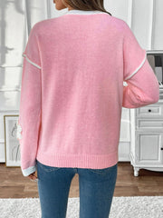Pink V-neck knit sweater with embroidered floral appliqué and white trim details.