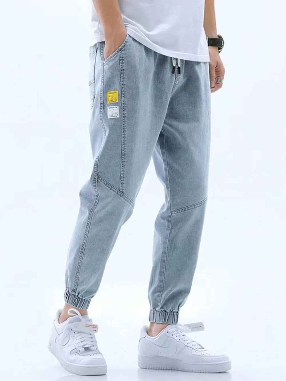Light blue relaxed fit drawstring jeans with elastic cuffs and patch details.