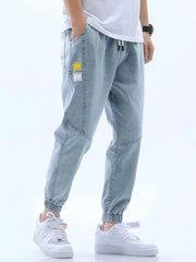 Light blue relaxed fit drawstring jeans with elastic cuffs and patch details.