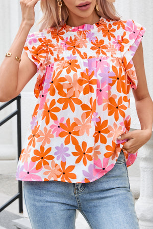 Multicolor floral smocked bodice flutter sleeve blouse with ruffled trim.