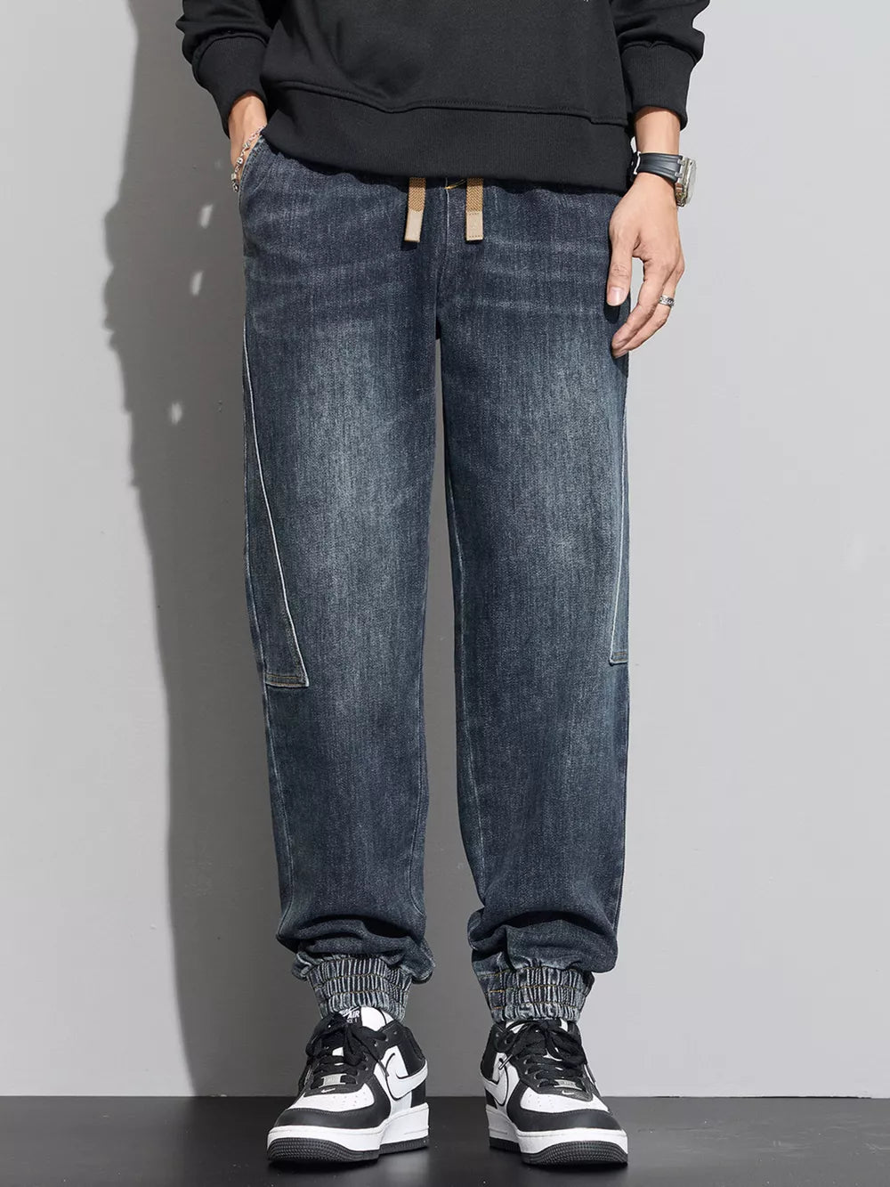 Casual drawstring waist denim joggers in black with elastic cuffs and white stitching detail.