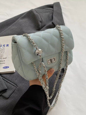Quilted chain crossbody clutch bag in light blue with silver hardware and a decorative ball charm.