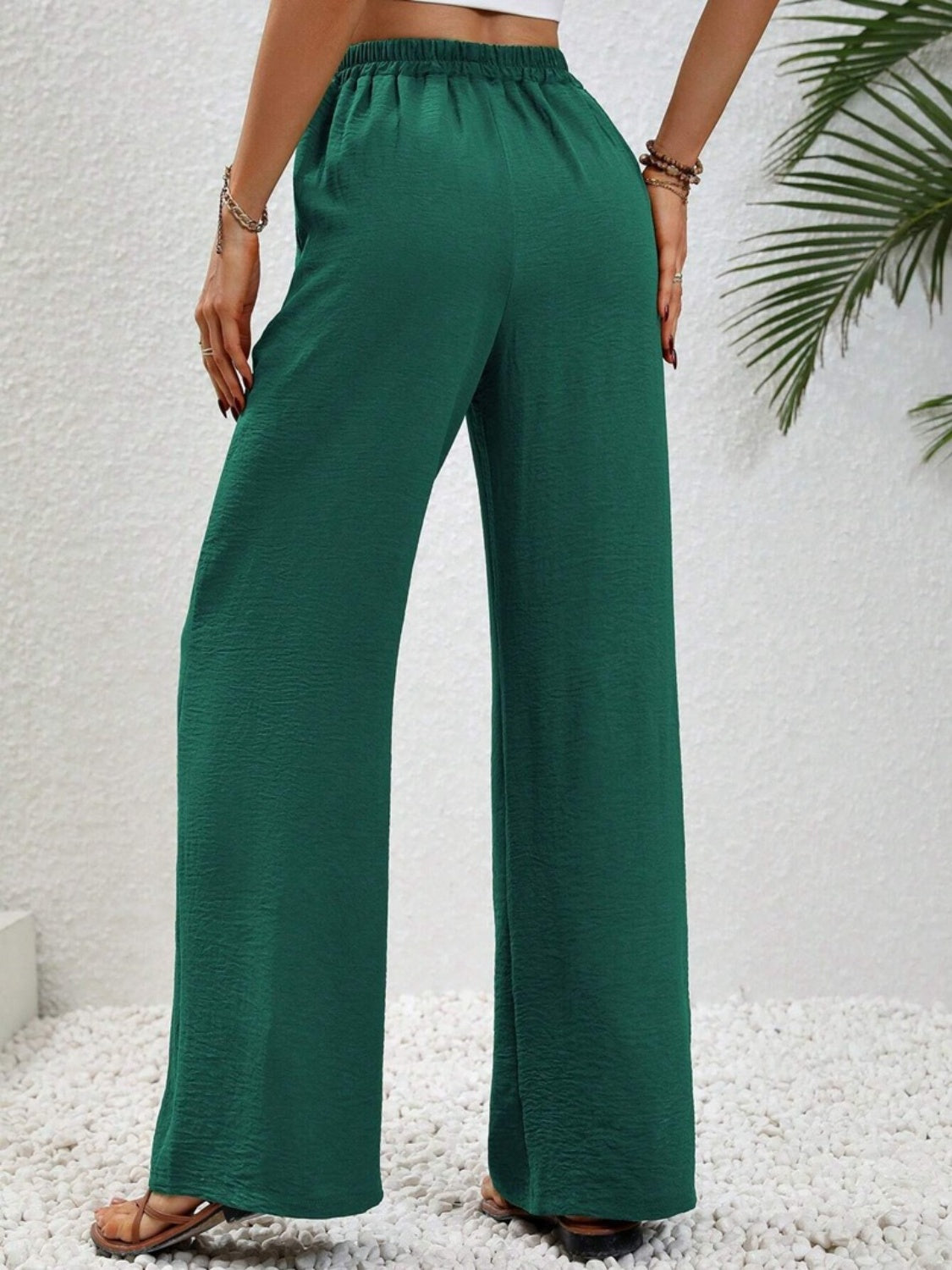 Dark green textured palazzo trousers with drawstring waist and wide legs.