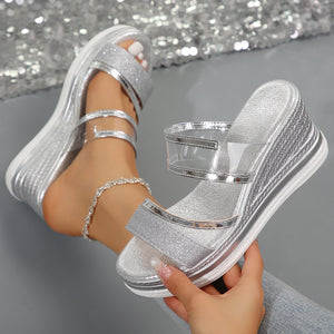 Silver glitter strap open-toe wedge sandals with clear ankle straps and a textured wedge.