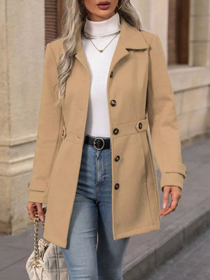 Camel button-up trench coat with cinched waist and button details, worn with jeans.