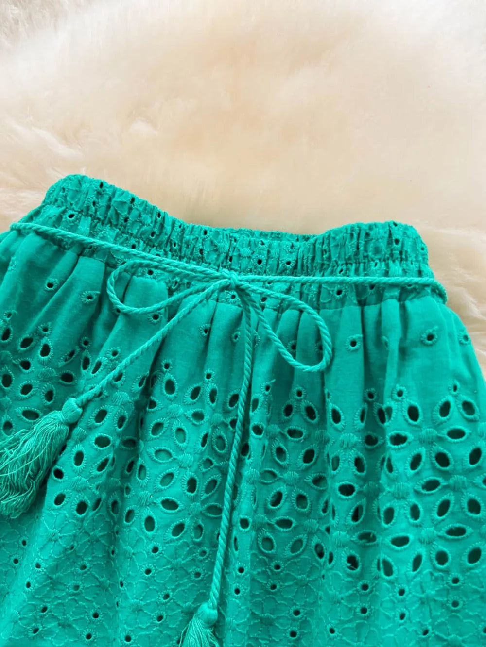 Green eyelet maxi skirt with tiered detail, drawstring waist, and tassels.