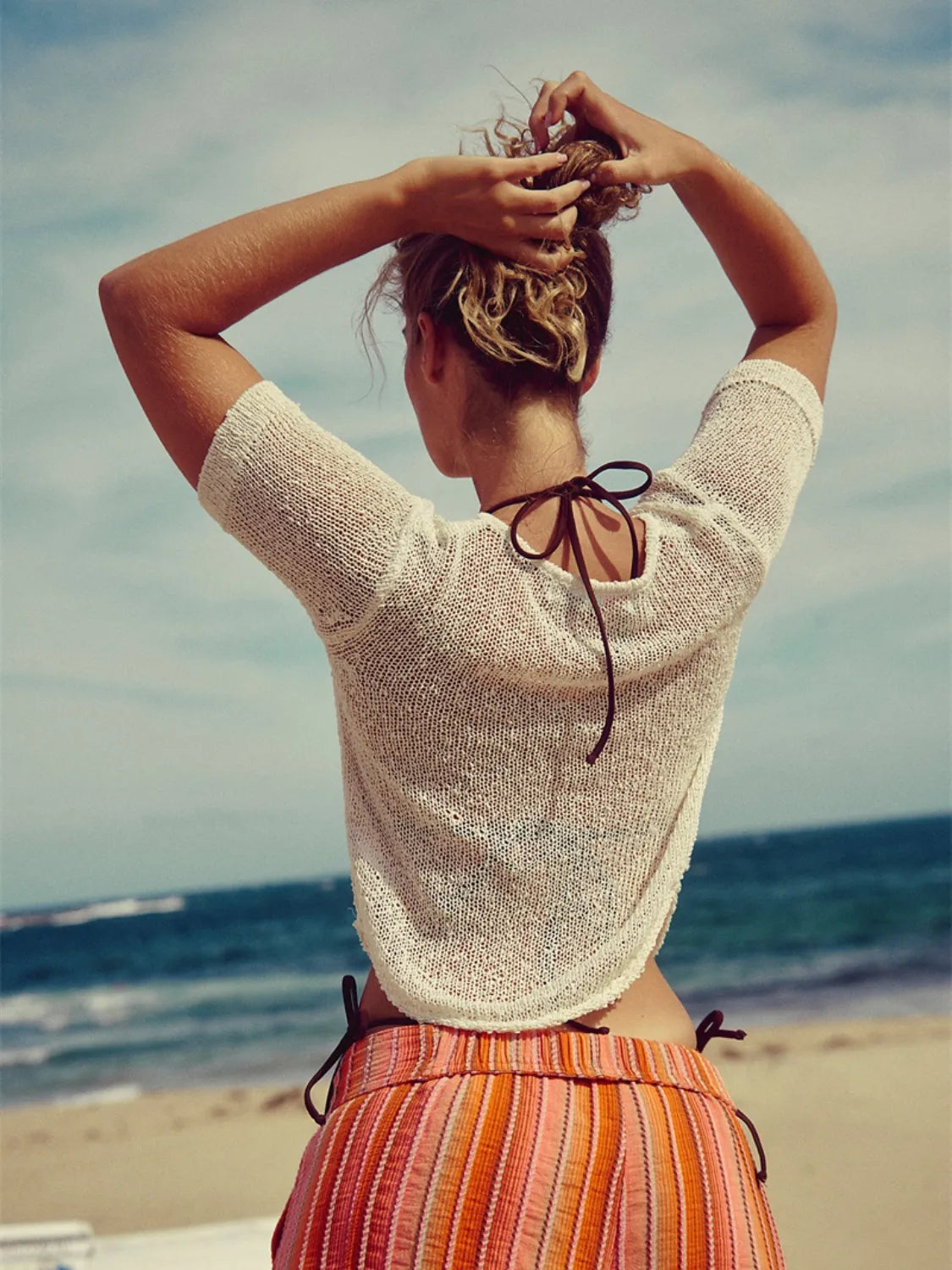 Chic knit sleeve blouse in white with a tie back detail, styled casually.