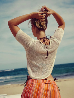 Chic knit sleeve blouse in white with a tie back detail, styled casually.