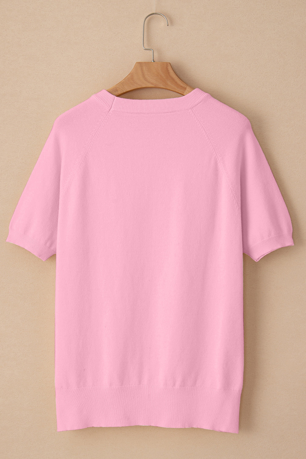 Pink knit top with short sleeves and crew neck, featuring daisy appliqué detail.