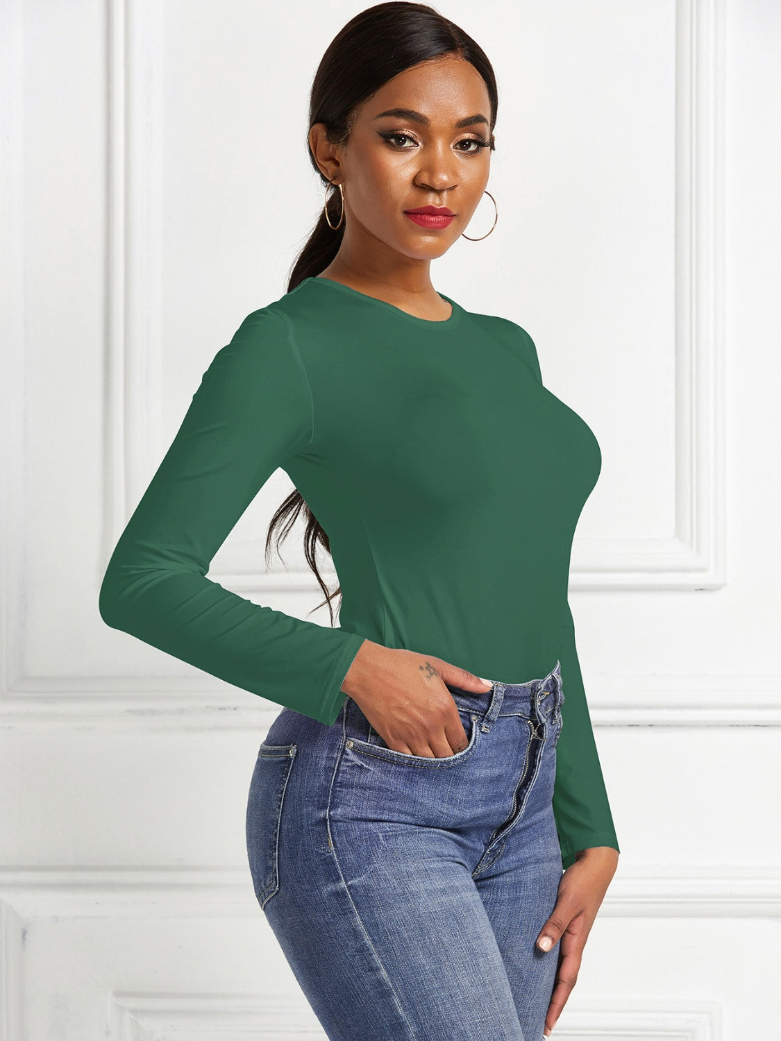 Dark Green ribbed jersey bodysuit with long sleeves and a crew neck, paired with blue jeans.