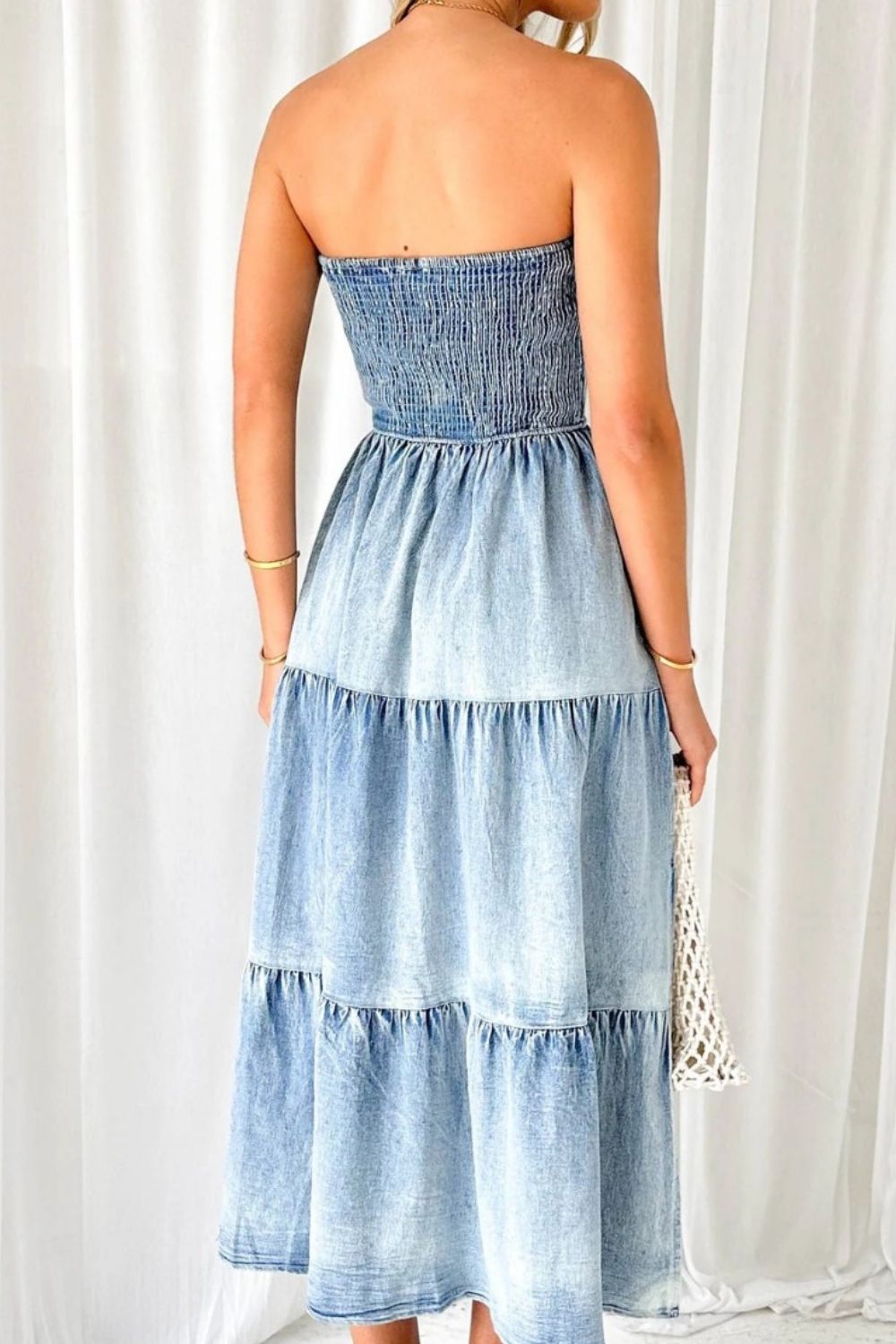 Smocked denim maxi dress in light blue with tiered skirt and strapless neckline.