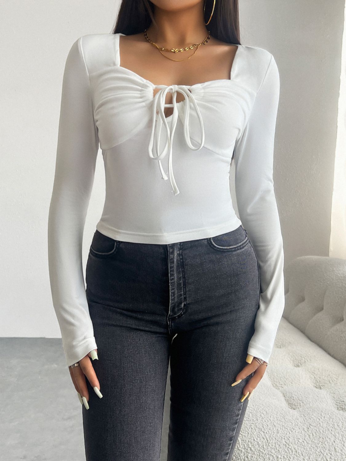 White ruched bustier long sleeve top with tie detail and square neckline.