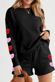 Black quilted loungewear set with heart appliqués on sleeves and shorts.