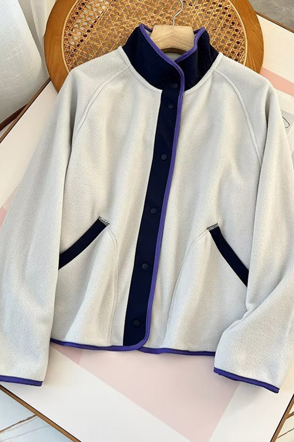 Light Gray fleece bomber jacket with navy and purple contrast trim and snap closure.