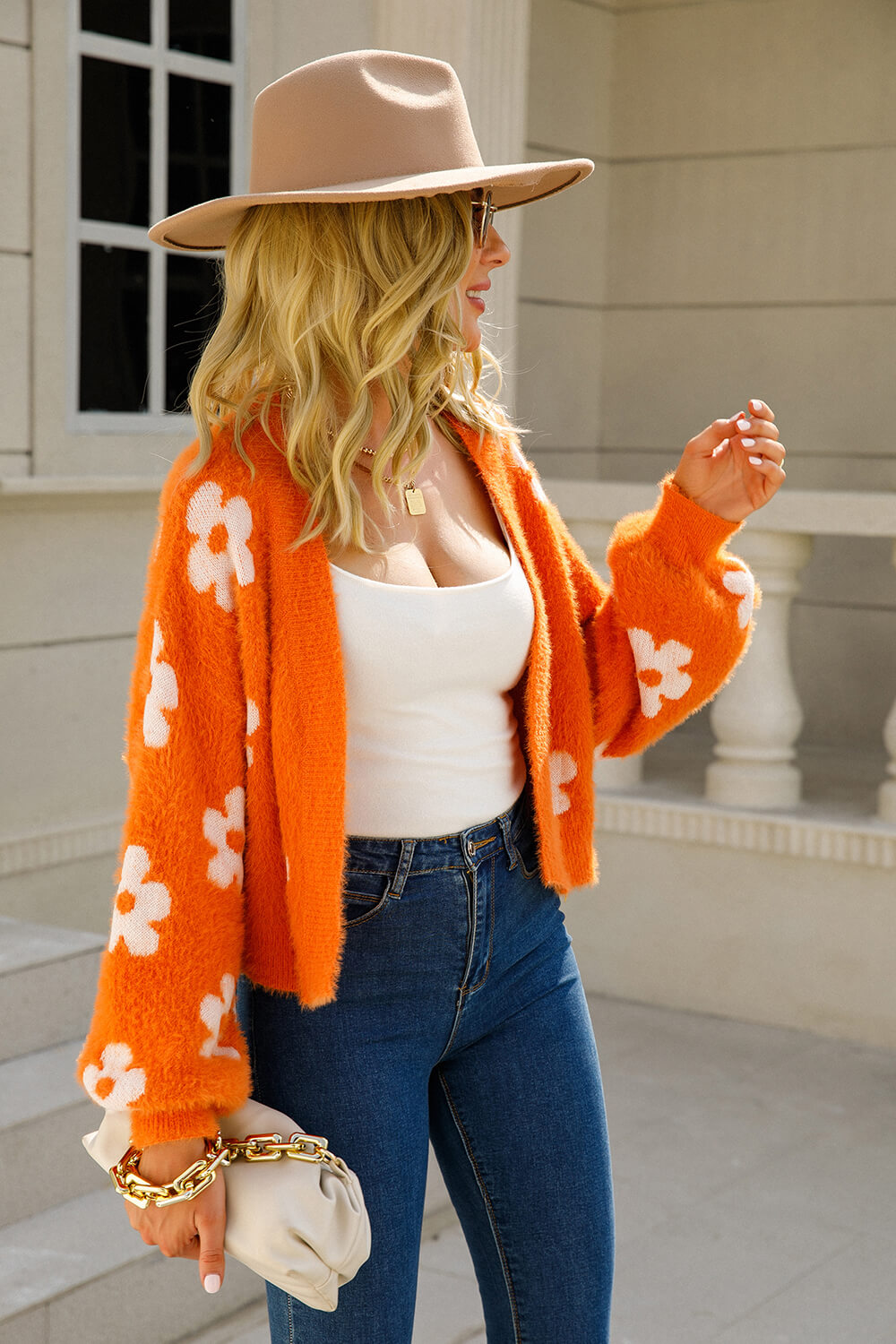 Orange fuzzy cropped cardigan with white floral pattern, open front, long sleeves.