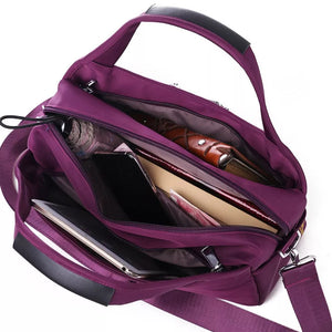 Spacious purple nylon tote bag with multiple compartments, holding a tablet, phone, and wallet.