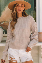 Tan knit sweater with diamond pattern on sleeves and ribbed texture.
