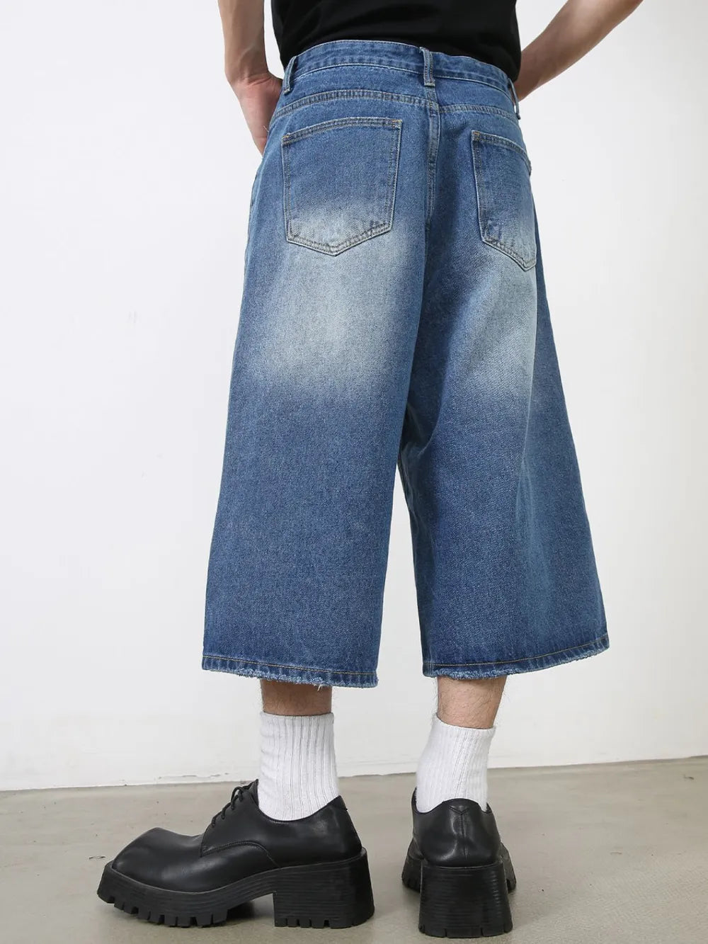Wide-leg denim culotte shorts in blue wash with distressed hem.