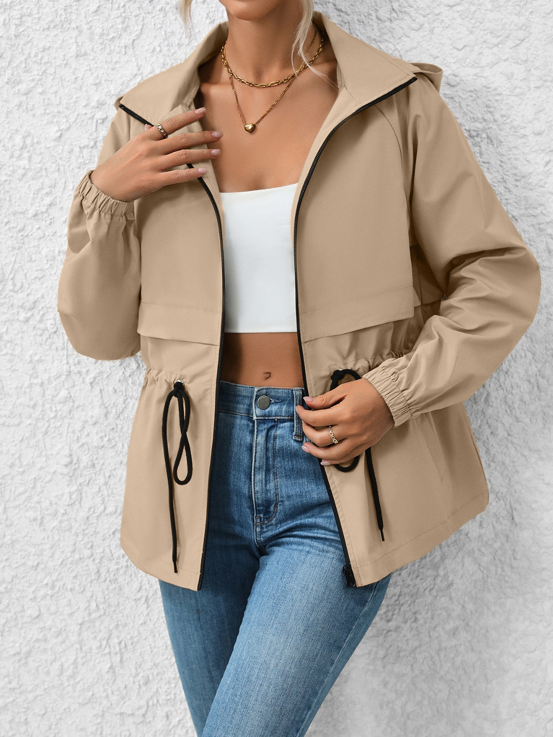 Khaki utility jacket with cinched waist, drawstring, hood, and black trim.