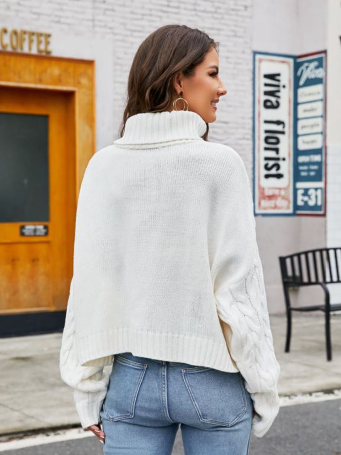 White cable-knit acrylic sweater with a high neck and cuffed sleeves.