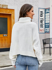 White cable-knit acrylic sweater with a high neck and cuffed sleeves.