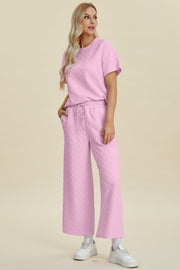 Pink textured knit lounge set with wide leg pants and a short sleeve top.