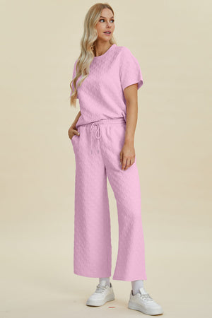 Pink textured knit lounge set with wide leg pants and a short sleeve top.
