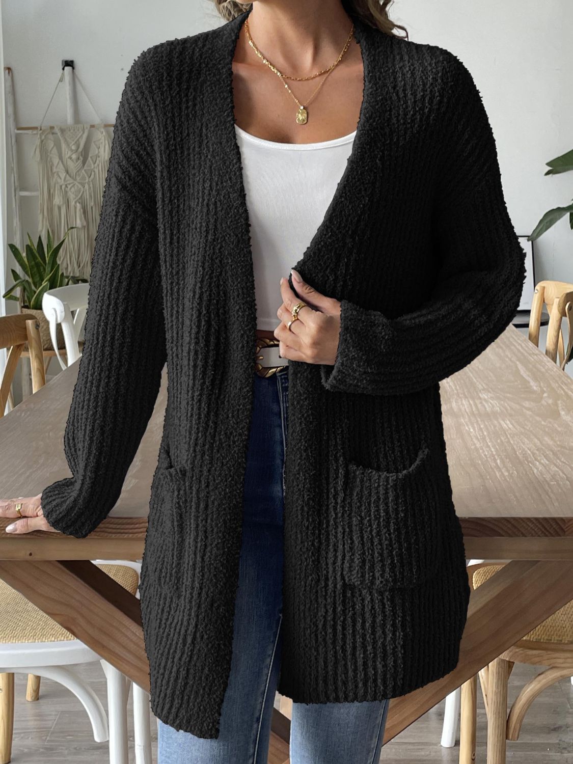 Black textured bouclé open-front cardigan with pockets and long sleeves.
