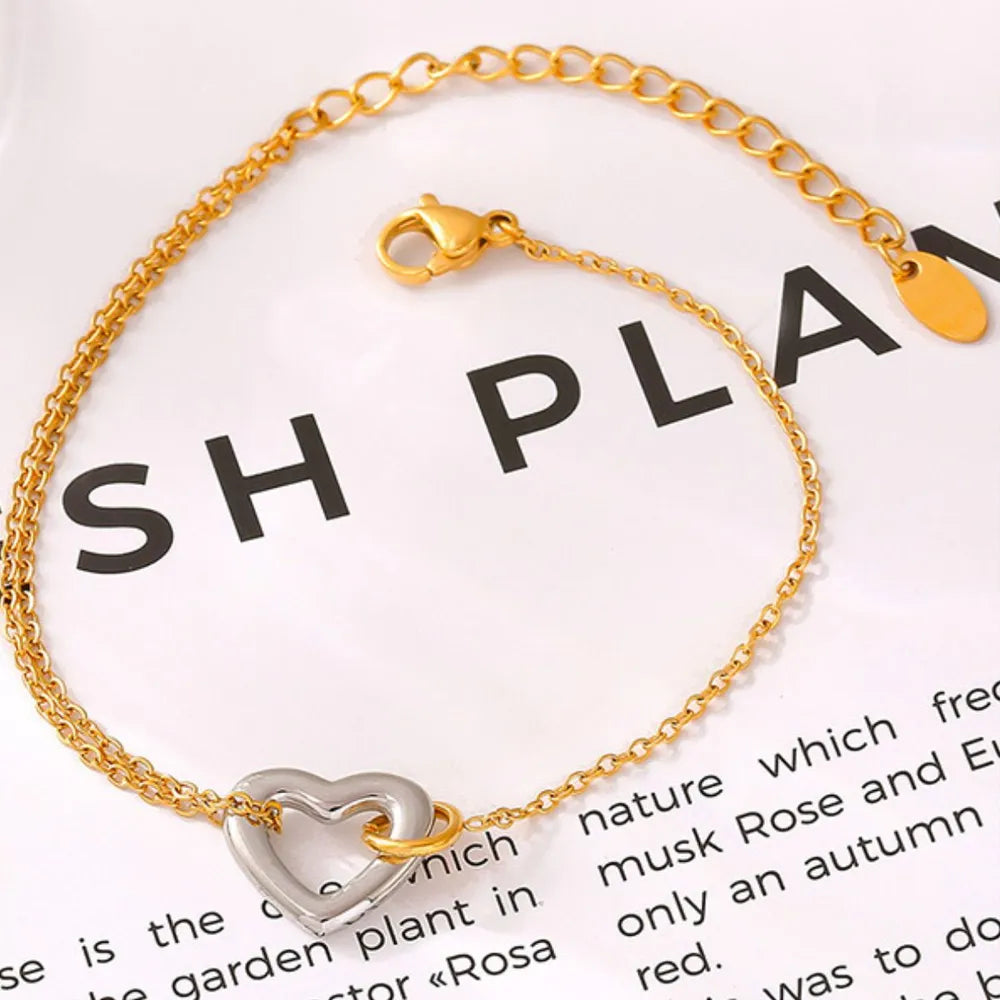 Gold two-tone heart charm bracelet with a delicate chain and lobster clasp.