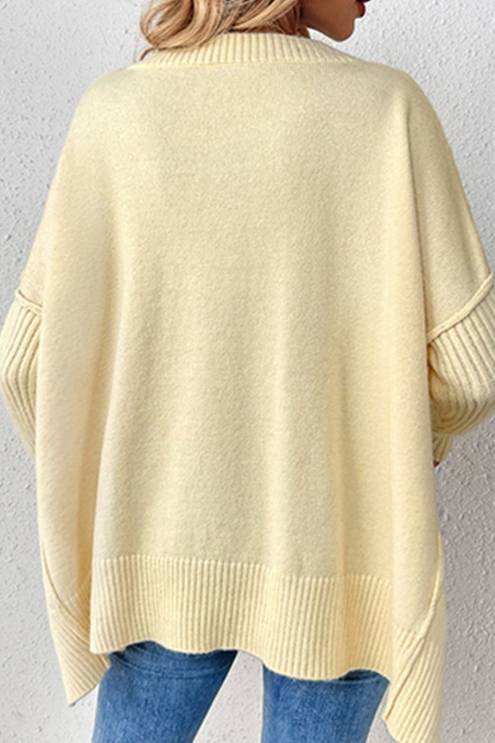 Light yellow acrylic knit sweater with asymmetric hemline and ribbed cuffs.