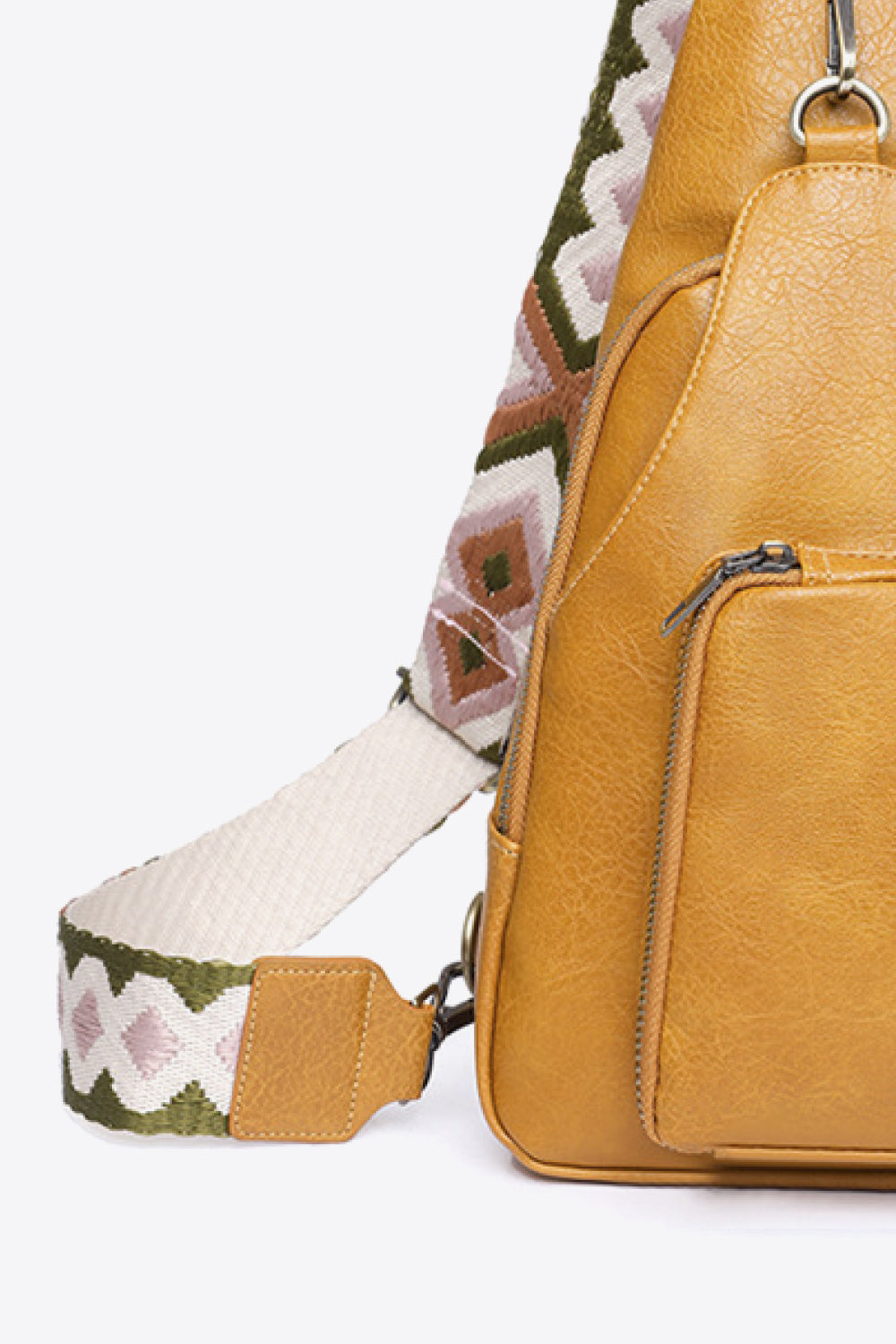 Ochre PU sling bag with a patterned strap and front zip pocket.