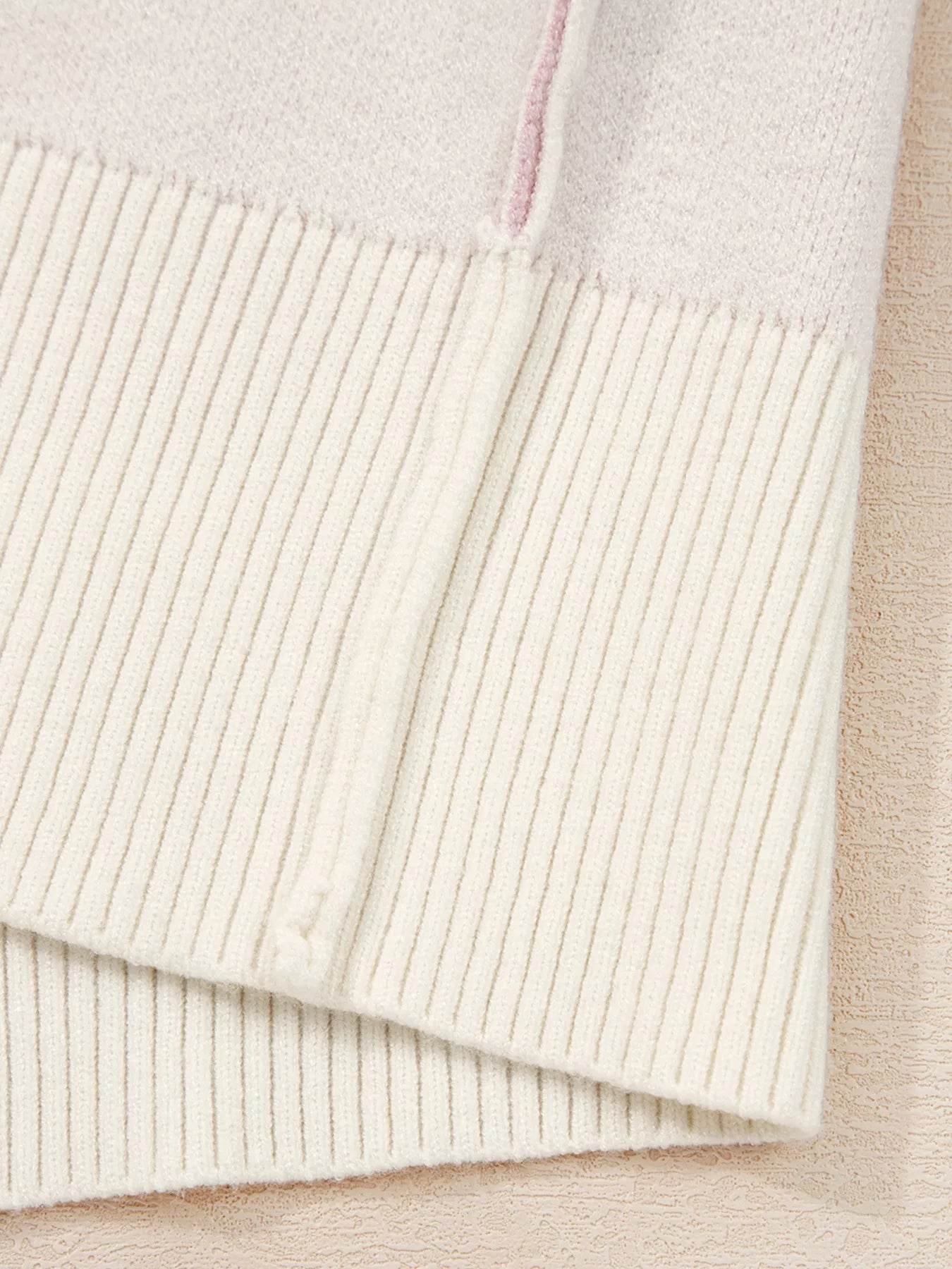 Beige acrylic blend sweater with ribbed hem and a subtle pink detail.