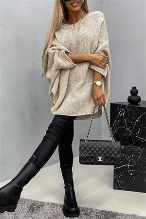Relaxed knit sweater in Khaki with cape sleeves and a round neckline, styled with black pants and boots.