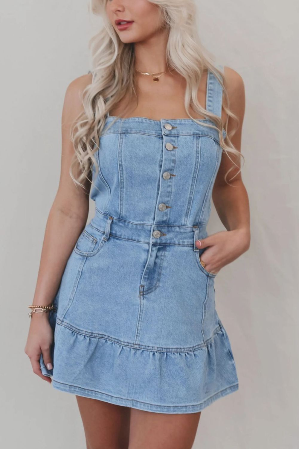 Button-front denim sundress with ruffle hem and square neckline in medium wash.