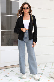 Black acrylic cardigan with fringe sleeves and open front, styled with a white crop top and jeans.