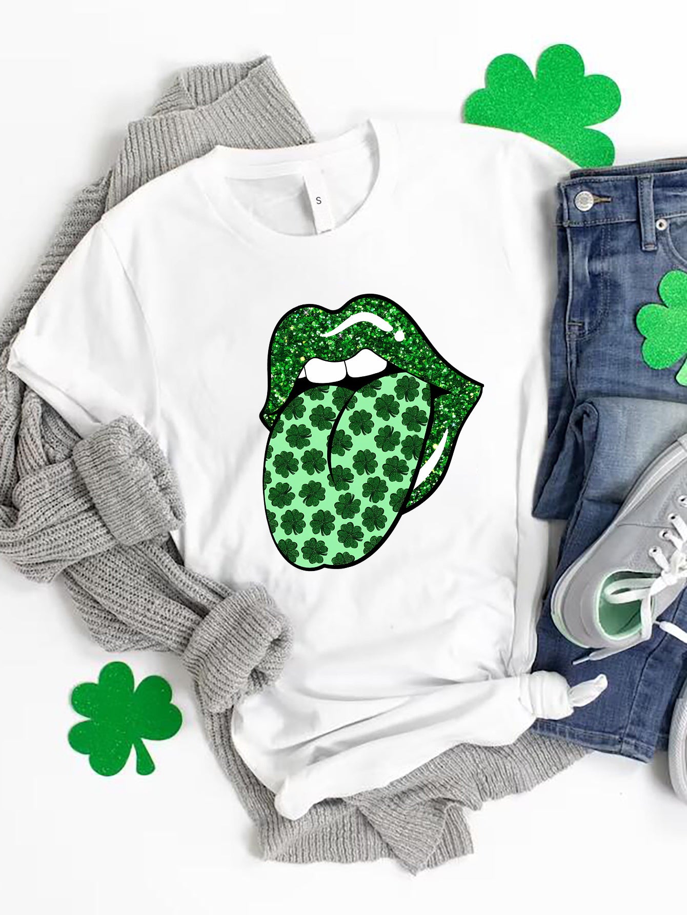 White graphic t-shirt with green glitter lips sticking out a tongue covered in shamrocks.