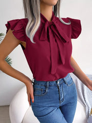 Burgundy pussy-bow blouse with ruffle sleeves, styled with jeans.
