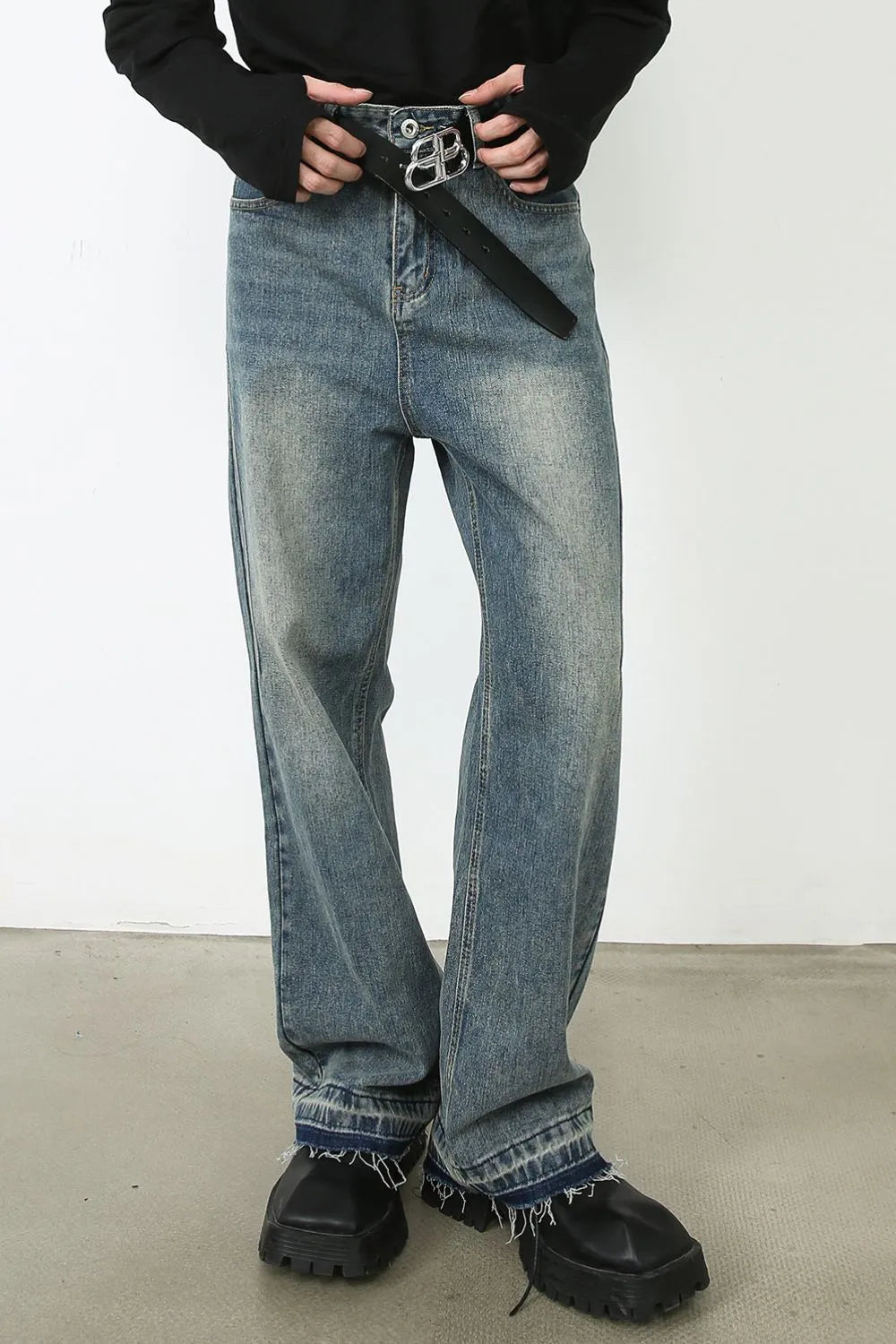 Distressed wide-leg denim jeans in medium wash with raw hem and a black belt.