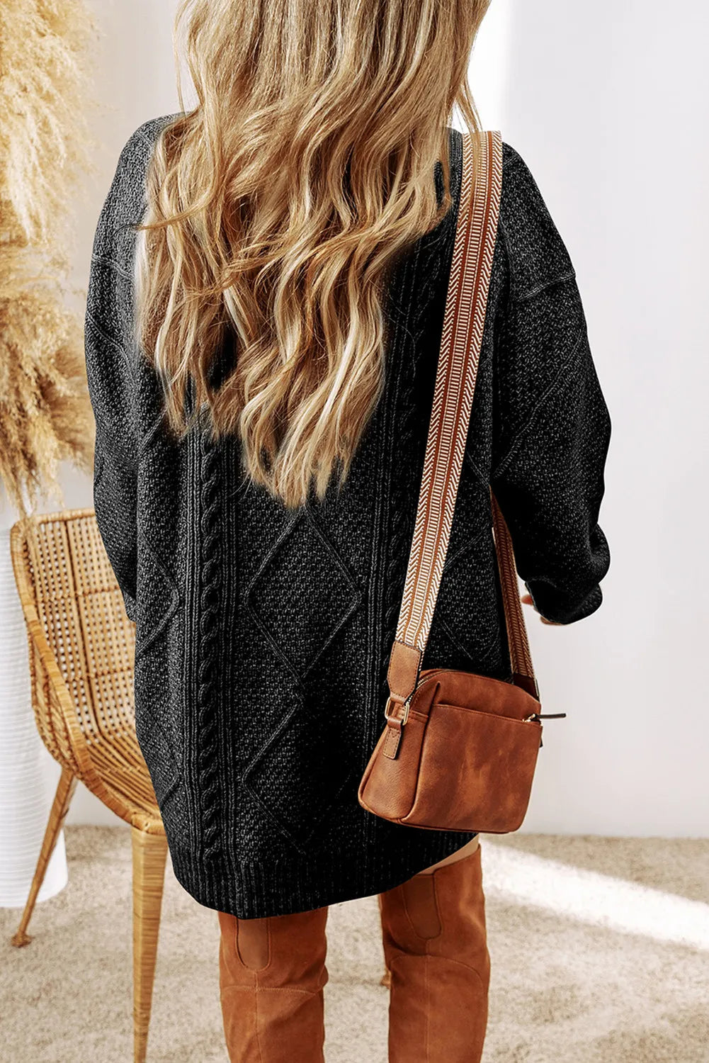Black cable knit sweater dress with diamond pattern detail and long sleeves.