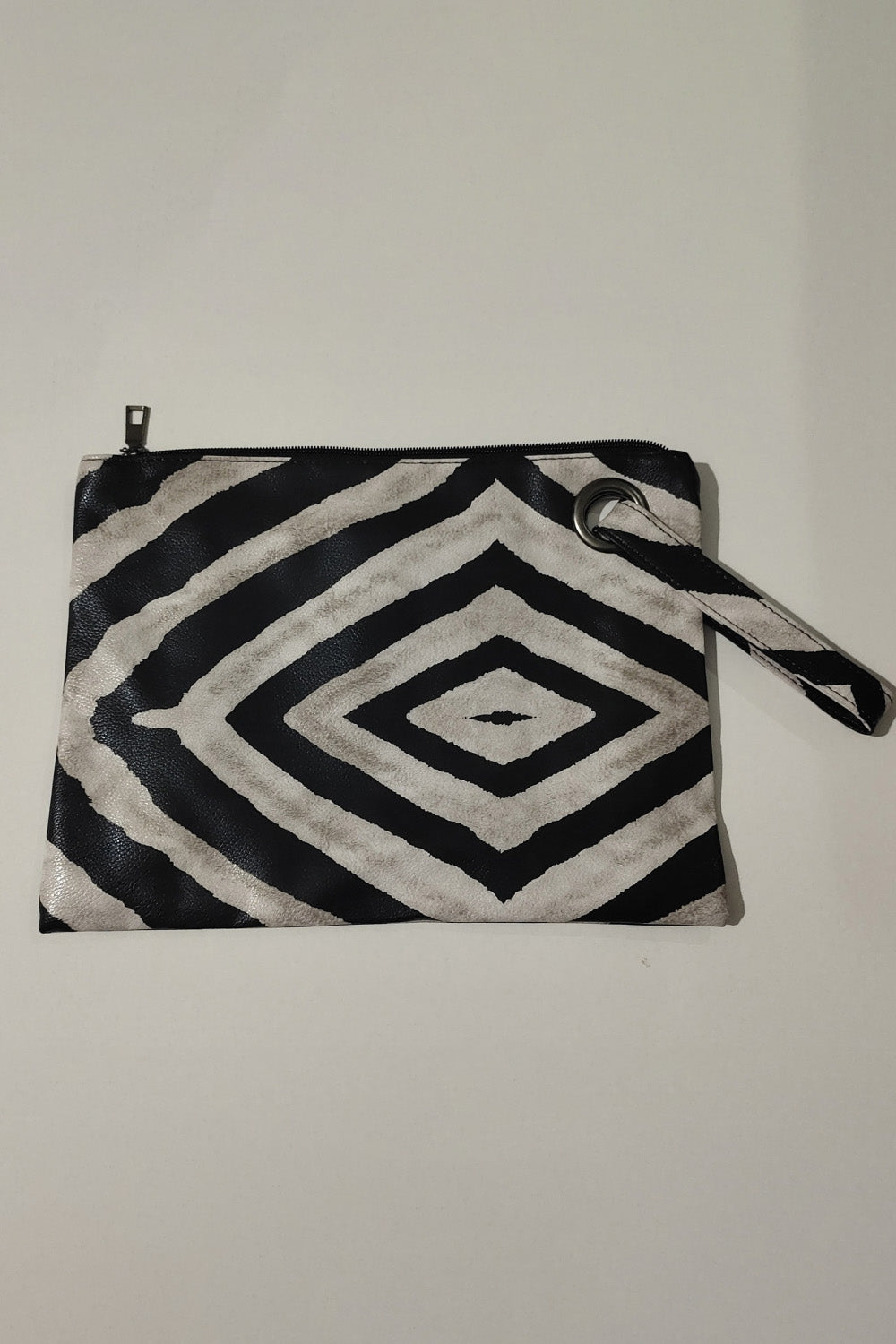 Clutch bag with black and white zebra print, wristlet strap, and grommet detail.